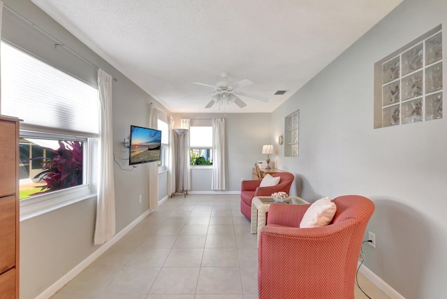 living area featuring a ceiling fan, light tile patterned flooring, and baseboards