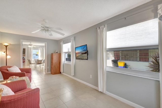 living room with light tile patterned floors, ceiling fan, and baseboards