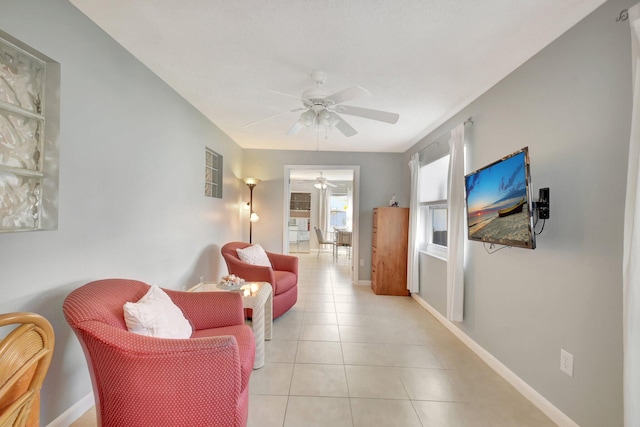 living room with ceiling fan, light tile patterned flooring, and baseboards
