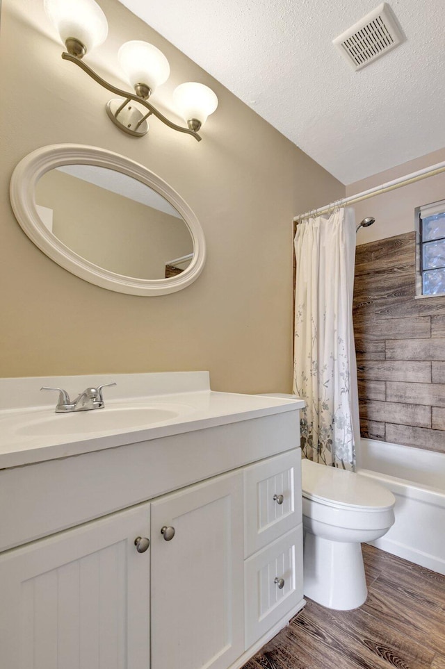 bathroom featuring vanity, toilet, wood finished floors, a textured ceiling, and shower / bath combo