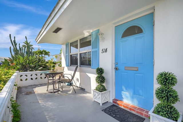 view of exterior entry with covered porch and stucco siding