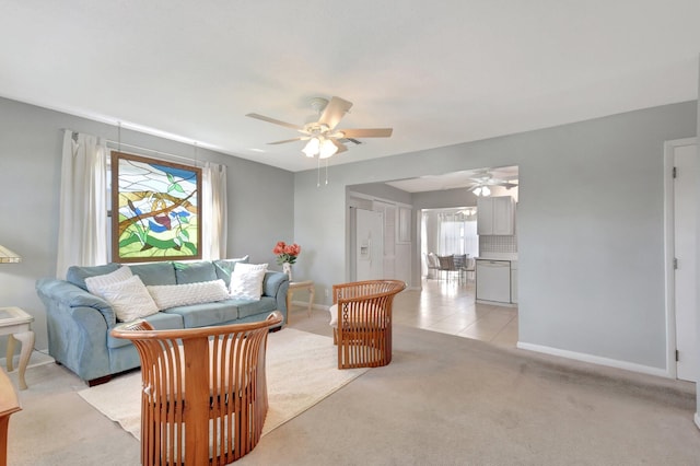 living area with ceiling fan, light colored carpet, and baseboards