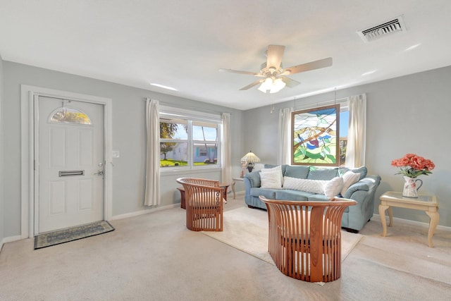 living area with ceiling fan, light carpet, and baseboards