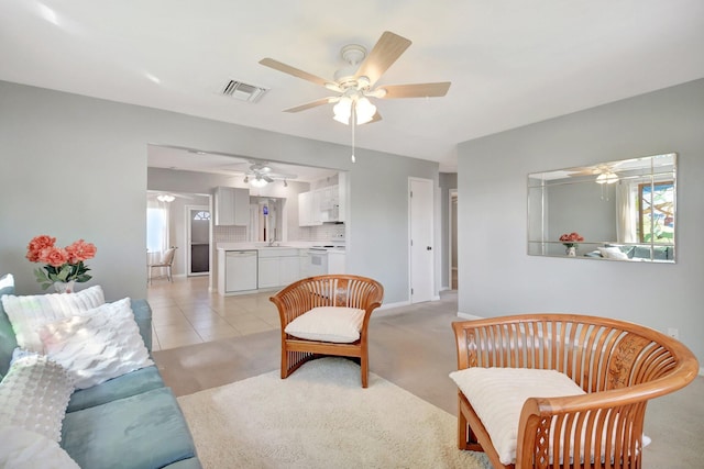 living area with a ceiling fan, light carpet, baseboards, and light tile patterned floors