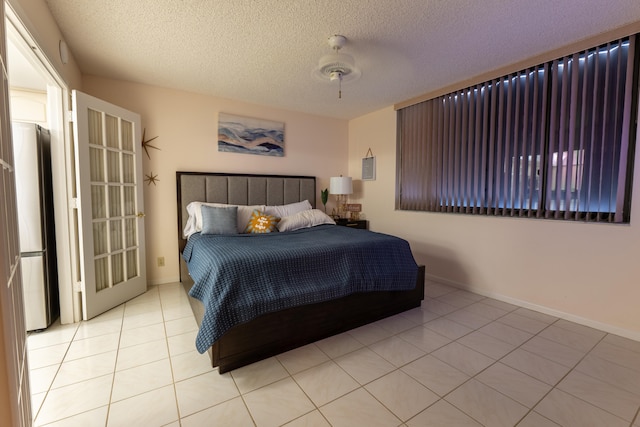 3120 N A1A Unit 1004, Hutchinson Island, FL 34949 - bedroom with light tile patterned flooring, a textured ceiling, freestanding refrigerator, and a ceiling fan