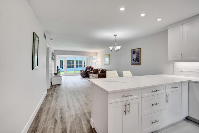 kitchen with a peninsula, white cabinetry, a chandelier, recessed lighting, and light stone countertops