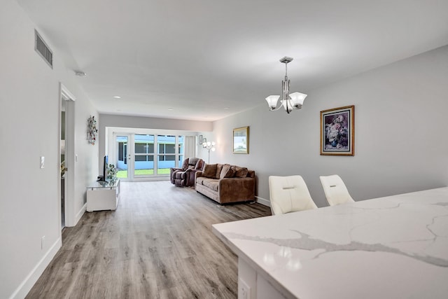 dining area featuring a chandelier, light wood-style flooring, and baseboards