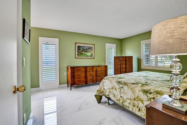bedroom featuring marble look tile flooring, multiple windows, and baseboards