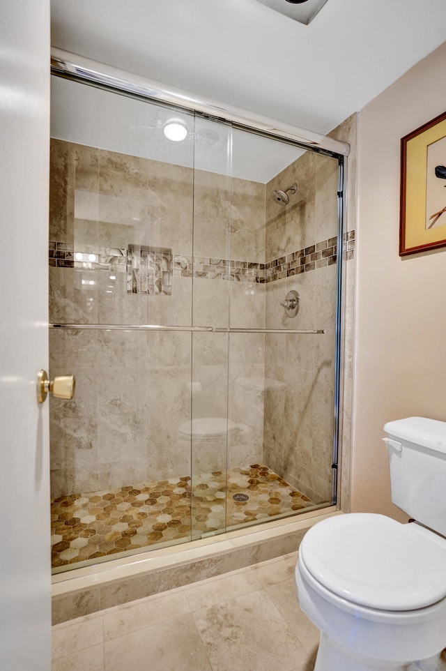 bathroom featuring toilet and a shower stall