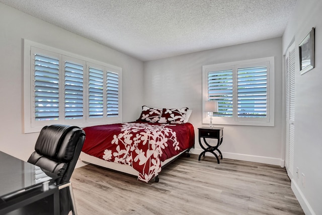 bedroom featuring wood finished floors, a textured ceiling, and baseboards