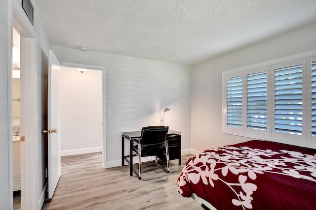 bedroom with wood finished floors, a textured ceiling, and baseboards