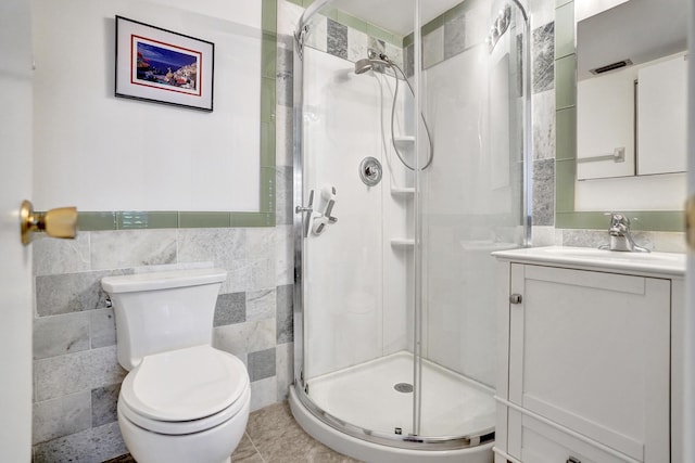 full bathroom featuring tile walls, a stall shower, vanity, and toilet