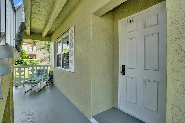 doorway to property featuring stucco siding and covered porch