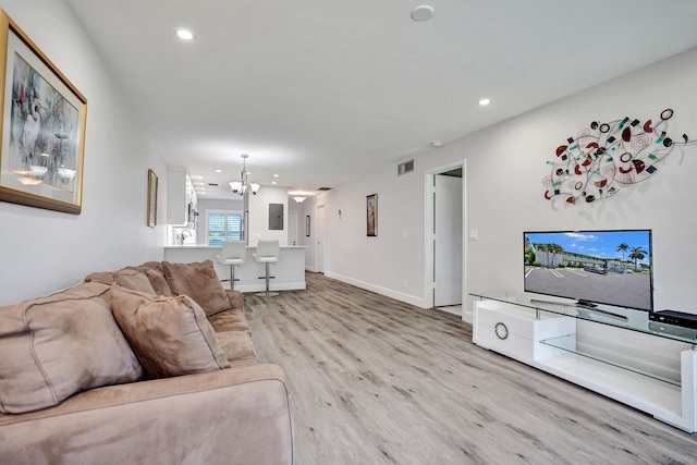 living room featuring light wood-style flooring, recessed lighting, a chandelier, and baseboards