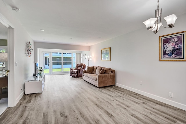 living room with wood finished floors, a chandelier, and baseboards