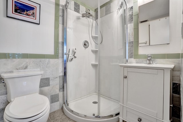 full bathroom featuring tile walls, a stall shower, toilet, and vanity