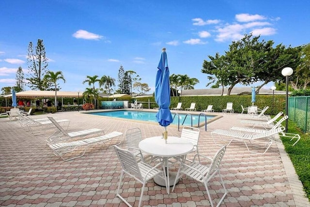community pool with fence and a patio area