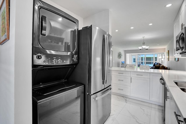 kitchen featuring stacked washer and clothes dryer, appliances with stainless steel finishes, white cabinets, light marble finish floors, and recessed lighting