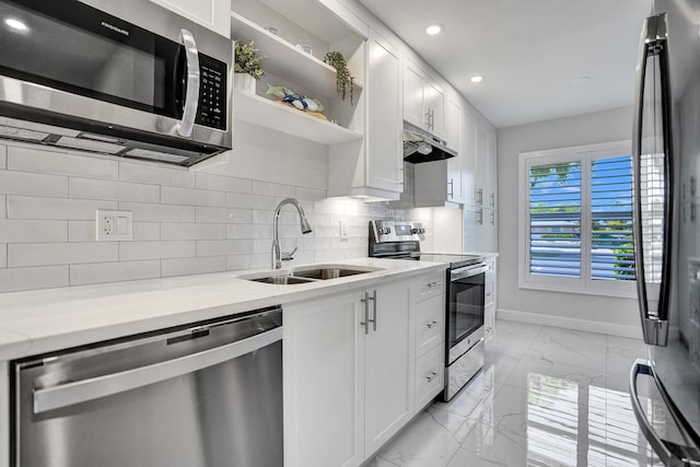 kitchen with stainless steel appliances, a sink, light marble finish flooring, under cabinet range hood, and baseboards