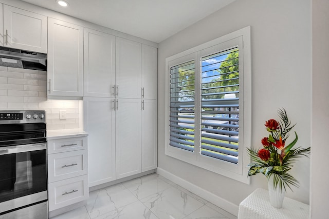 kitchen with under cabinet range hood, healthy amount of natural light, tasteful backsplash, light countertops, and recessed lighting