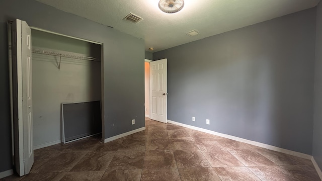 1500 SW Bermel Ave, Port Saint Lucie, FL 34953 - unfurnished bedroom with a closet, baseboards, a textured ceiling, and dark tile patterned flooring