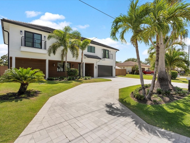 8 Leeward Cir, Tequesta, FL 33469 - view of front facade with an attached garage, stucco siding, a front yard, decorative driveway, and a balcony