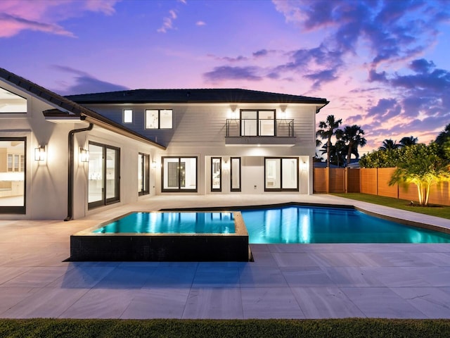 8 Leeward Cir, Tequesta, FL 33469 - back of house at dusk with a balcony, a patio, and a fenced backyard