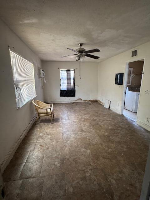 spare room with washing machine and dryer, a ceiling fan, and baseboards
