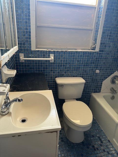 full bath featuring tile walls, a sink, tile patterned flooring, and toilet