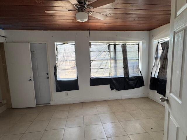 spare room with wood ceiling, a ceiling fan, plenty of natural light, and light tile patterned flooring