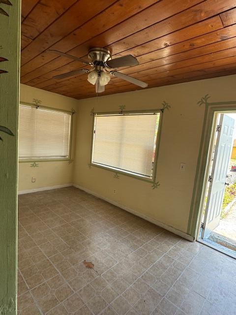 empty room with wooden ceiling, ceiling fan, baseboards, and tile patterned flooring