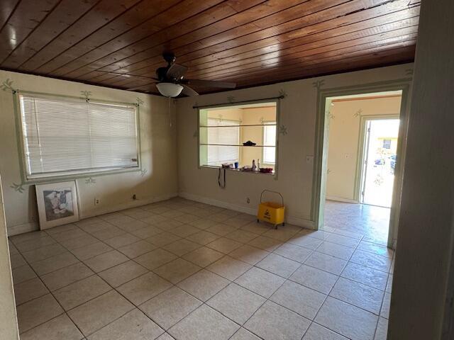 unfurnished room with wood ceiling, light tile patterned floors, plenty of natural light, and ceiling fan