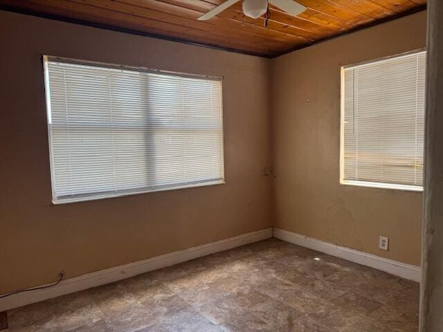 empty room featuring wooden ceiling, ceiling fan, and baseboards