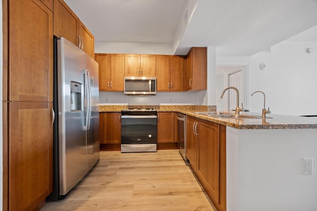 350 N Federal Hwy SE Unit 506, Boynton Beach, FL 33435 - kitchen featuring stainless steel appliances, a sink, brown cabinetry, light wood finished floors, and stone countertops