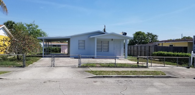 717 Hollywood Pl, West Palm Beach, FL 33405 - view of front of property with a fenced front yard, a gate, an attached carport, and concrete driveway