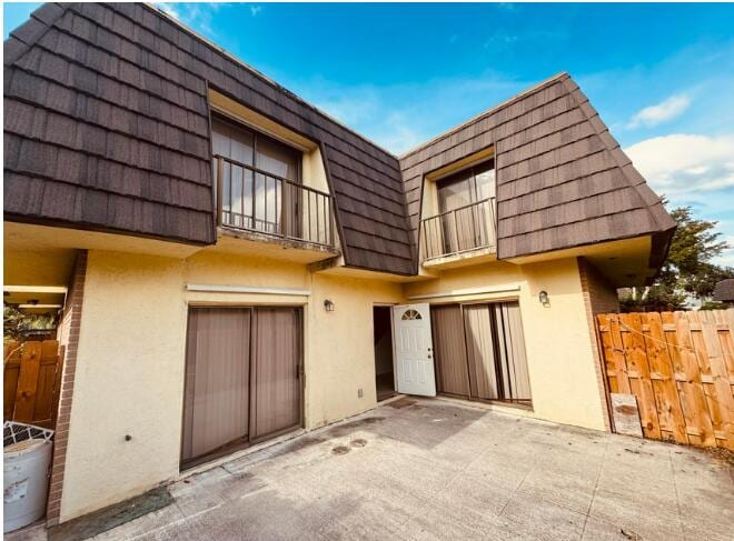 4626 Cherry Rd, West Palm Beach, FL 33417 - rear view of property featuring stucco siding, mansard roof, a patio area, and a balcony