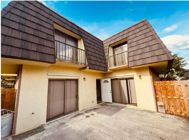 4626 Cherry Rd, West Palm Beach, FL 33417 - rear view of property featuring stucco siding, mansard roof, a patio area, and a balcony