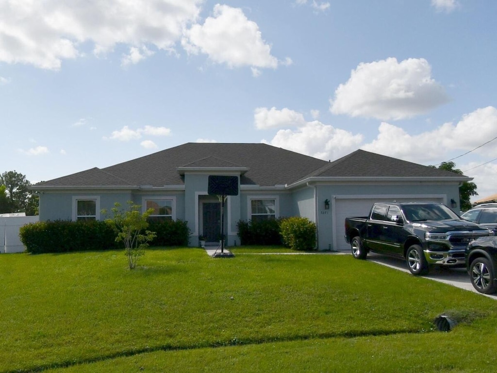ranch-style home featuring stucco siding, an attached garage, and driveway