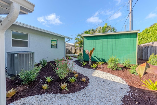view of yard with cooling unit, fence, and an outbuilding