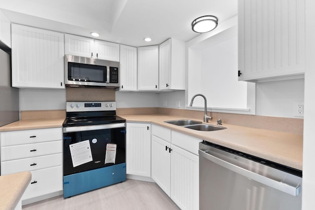 kitchen featuring stainless steel appliances, a sink, recessed lighting, white cabinetry, and light countertops