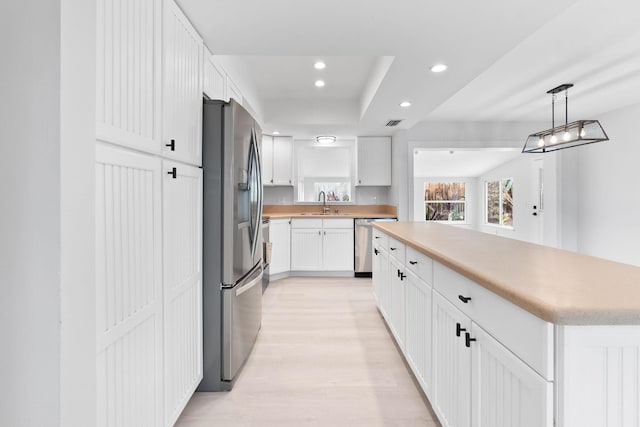 kitchen featuring appliances with stainless steel finishes, light countertops, recessed lighting, white cabinetry, and light wood-type flooring