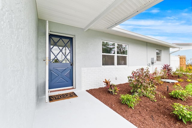 property entrance with stucco siding and brick siding