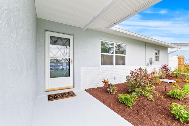 entrance to property featuring stucco siding and brick siding