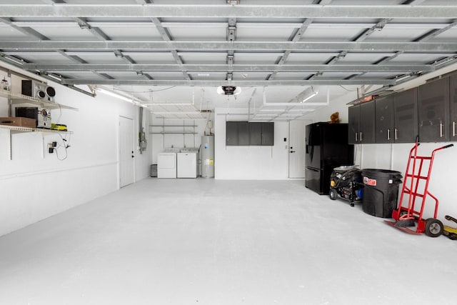 garage featuring electric water heater, washing machine and dryer, and freestanding refrigerator