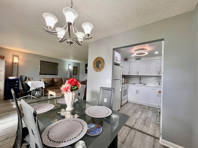 314 Chatham P, West Palm Beach, FL 33417 - dining room featuring a chandelier, light wood-type flooring, and a textured ceiling
