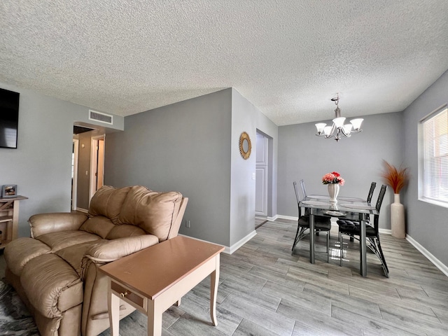314 Chatham P, West Palm Beach, FL 33417 - dining room featuring a chandelier, a textured ceiling, light wood-type flooring, and baseboards