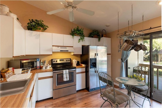 13045 Albright Ct Unit 12, Wellington, FL 33414 - kitchen featuring appliances with stainless steel finishes, under cabinet range hood, lofted ceiling, light wood-style flooring, and white cabinetry