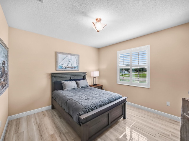 11416 SW Lake Park Dr, Port Saint Lucie, FL 34987 - bedroom with light wood finished floors, baseboards, and a textured ceiling