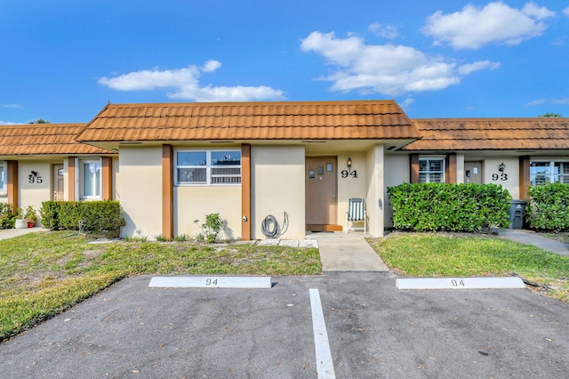 multi unit property featuring uncovered parking, a tiled roof, and stucco siding