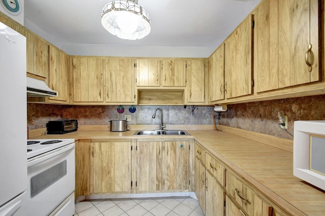 kitchen with under cabinet range hood, white appliances, a sink, light countertops, and light tile patterned floors